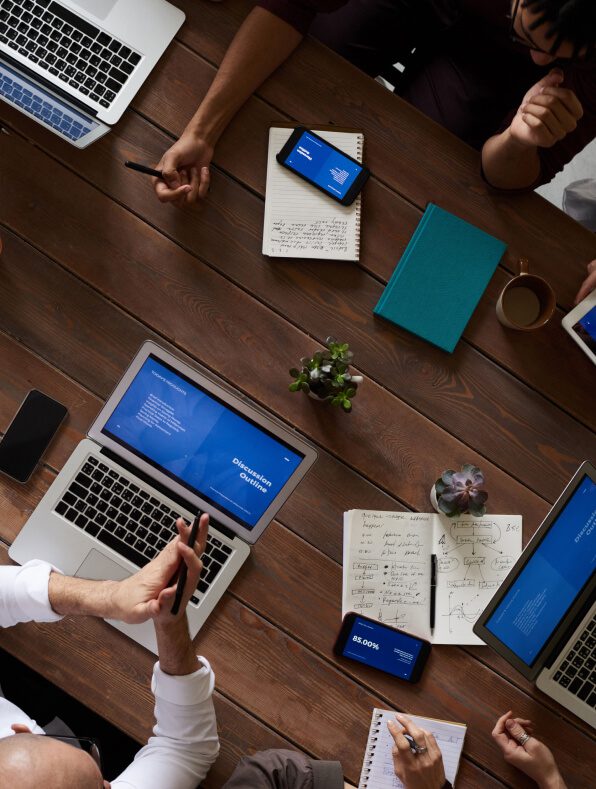 A team of business man sitting around a table with laptops, working together building strategic business plan at Peter Trifelly Certified Business Coach