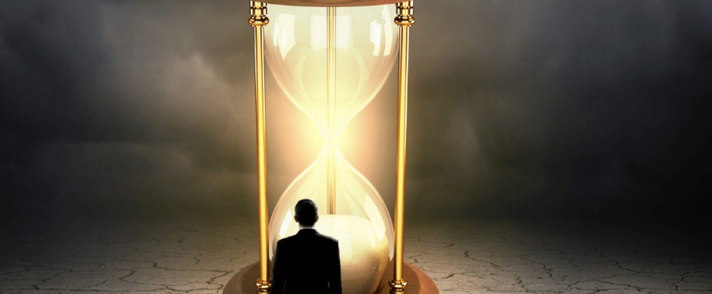 A man stands before a towering hourglass, symbolising the passage of time. What's your perspective of time?at Peter Trifelly Certified Business Coach